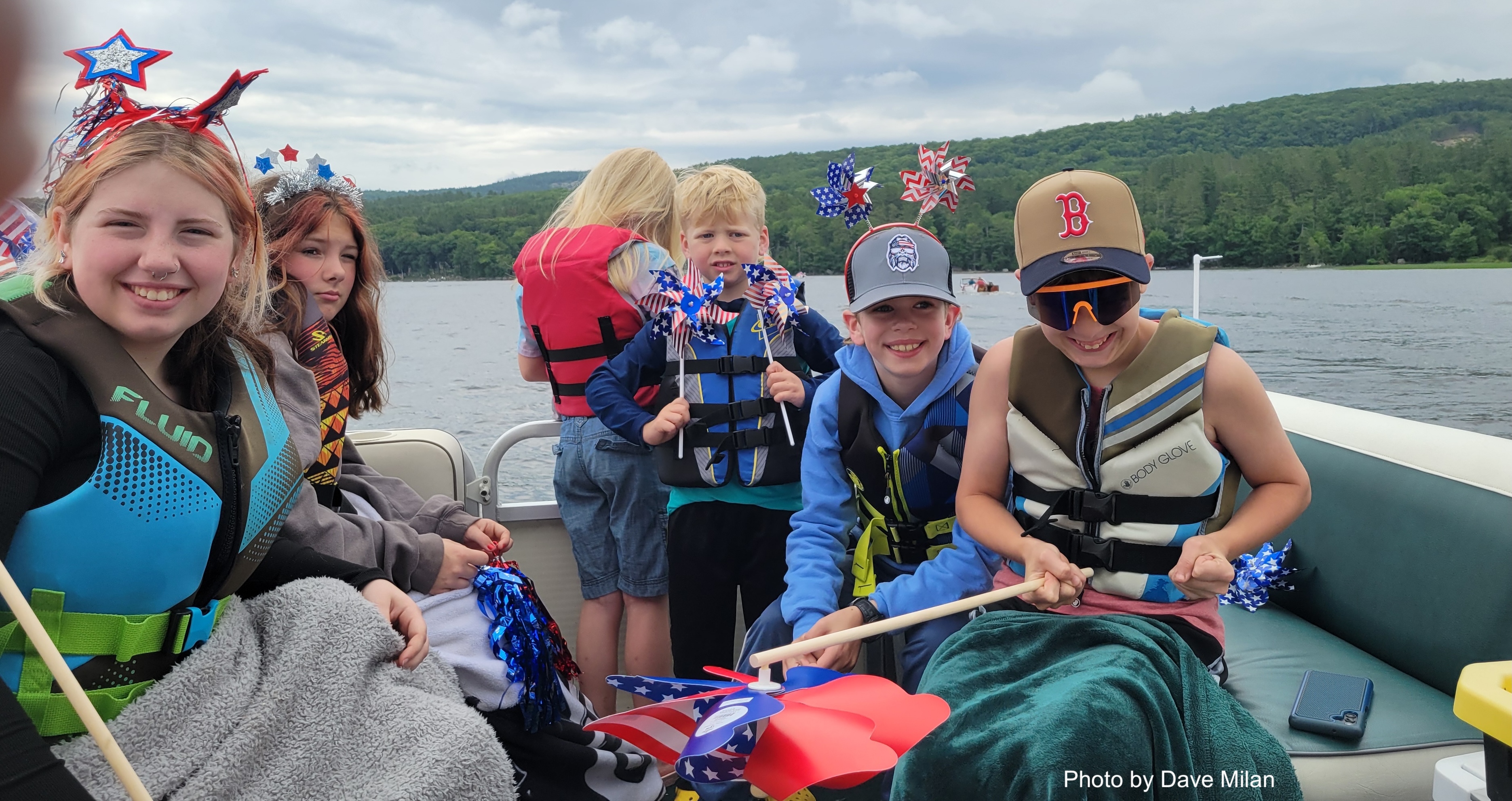 Children in life jackets celebrating on a boat with patriotic decorations