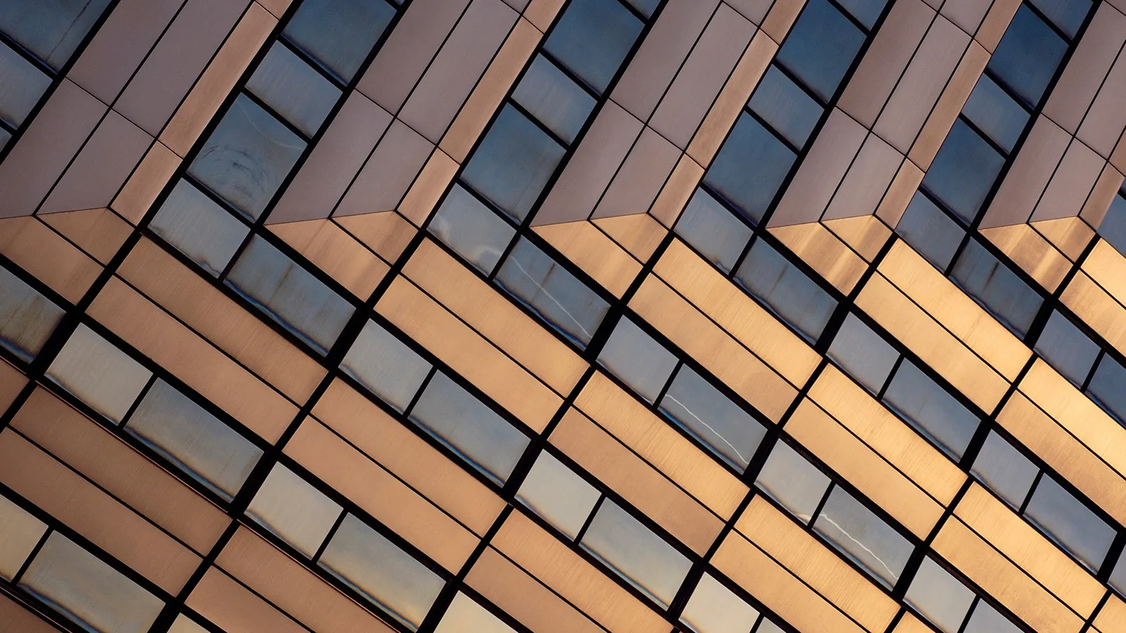 Modern office building, orange-grey coloured, reflecting sunshine.