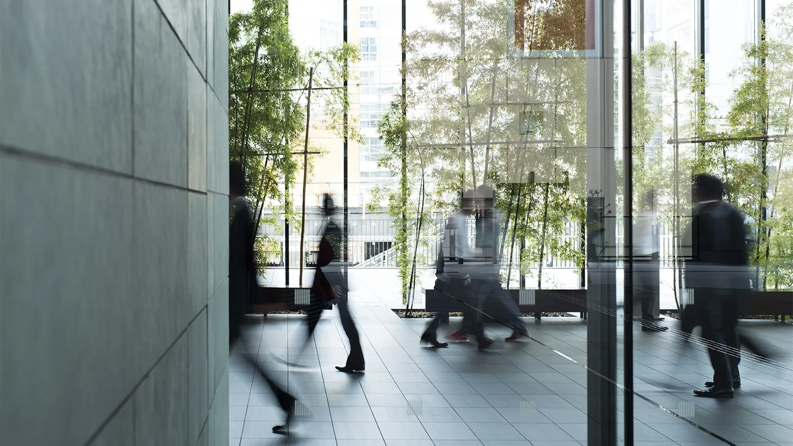Businesspeople walking across the foyer of an office building. Employment, restraints of trade concept.