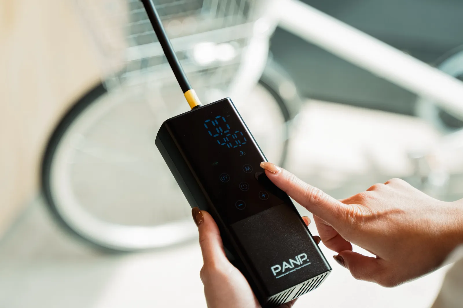 PANP RIDEを自転車のタイヤバルブに接続し、ボタンを押している様子