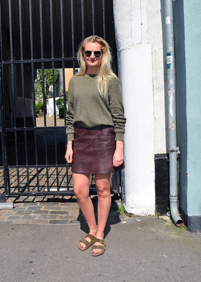 Street style danois à Aarhus, femme avec une jupe en cuir, une blouse cashmere kaki et des sandale en cuir.