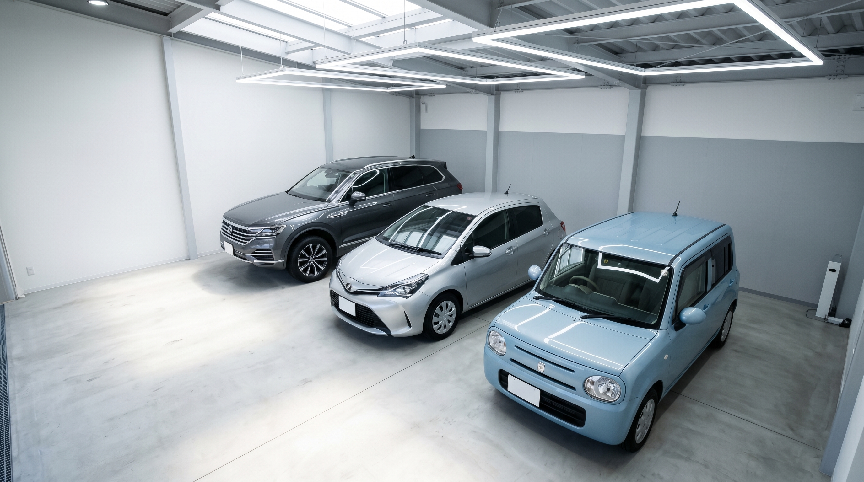 広々とした清潔な屋内のスタジオに、手前から軽自動車、コンパクトカー、大型SUVとサイズの異なる3台の車が綺麗に並んで駐車されている斜め上からの俯瞰シーン。