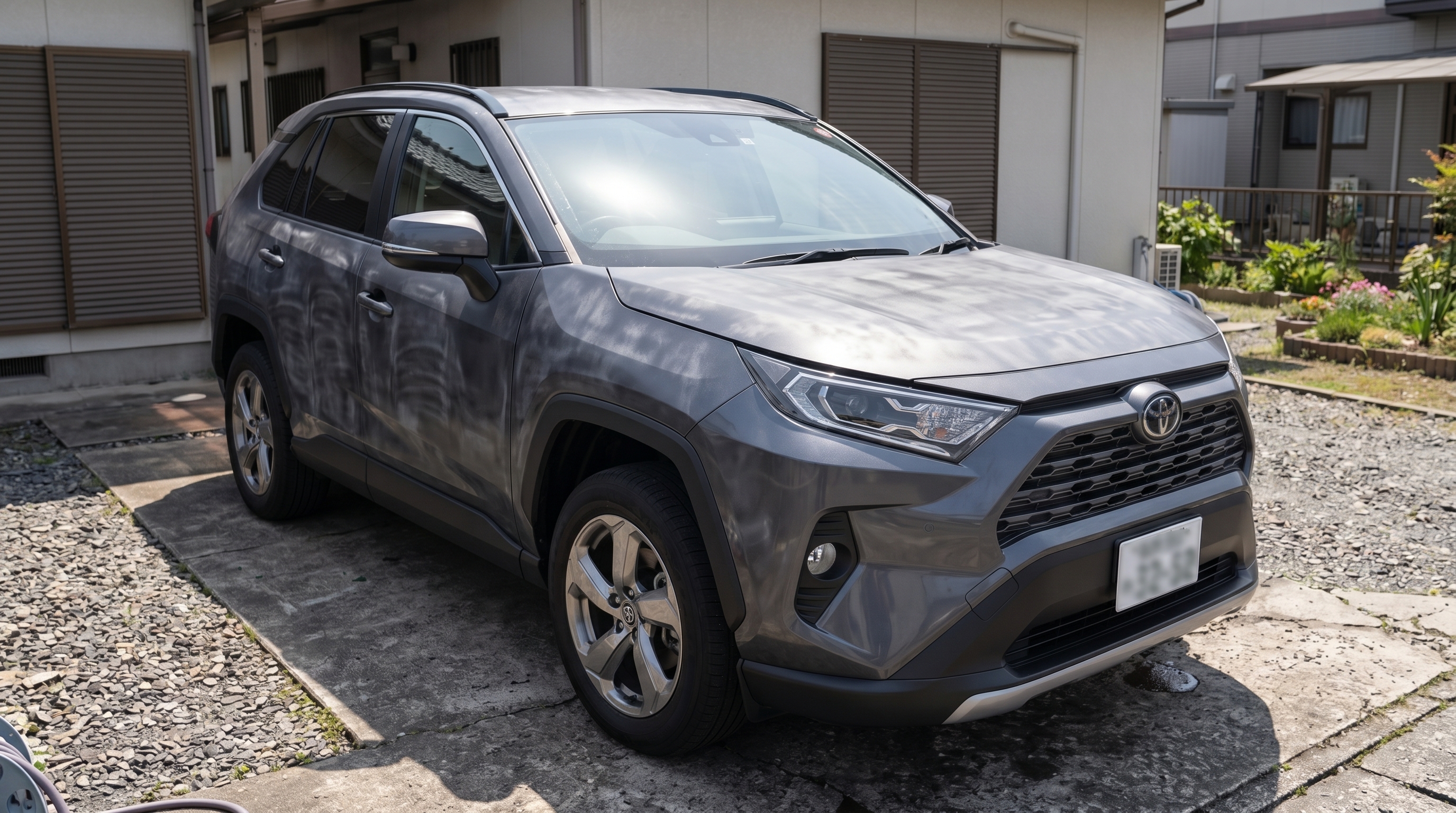 一般家庭の駐車場に停められたSUVをローアングルから捉えた様子。DIYのカーコーティングの失敗例として、ボディの表面に日光が当たり施工ムラが目立っているシーン。