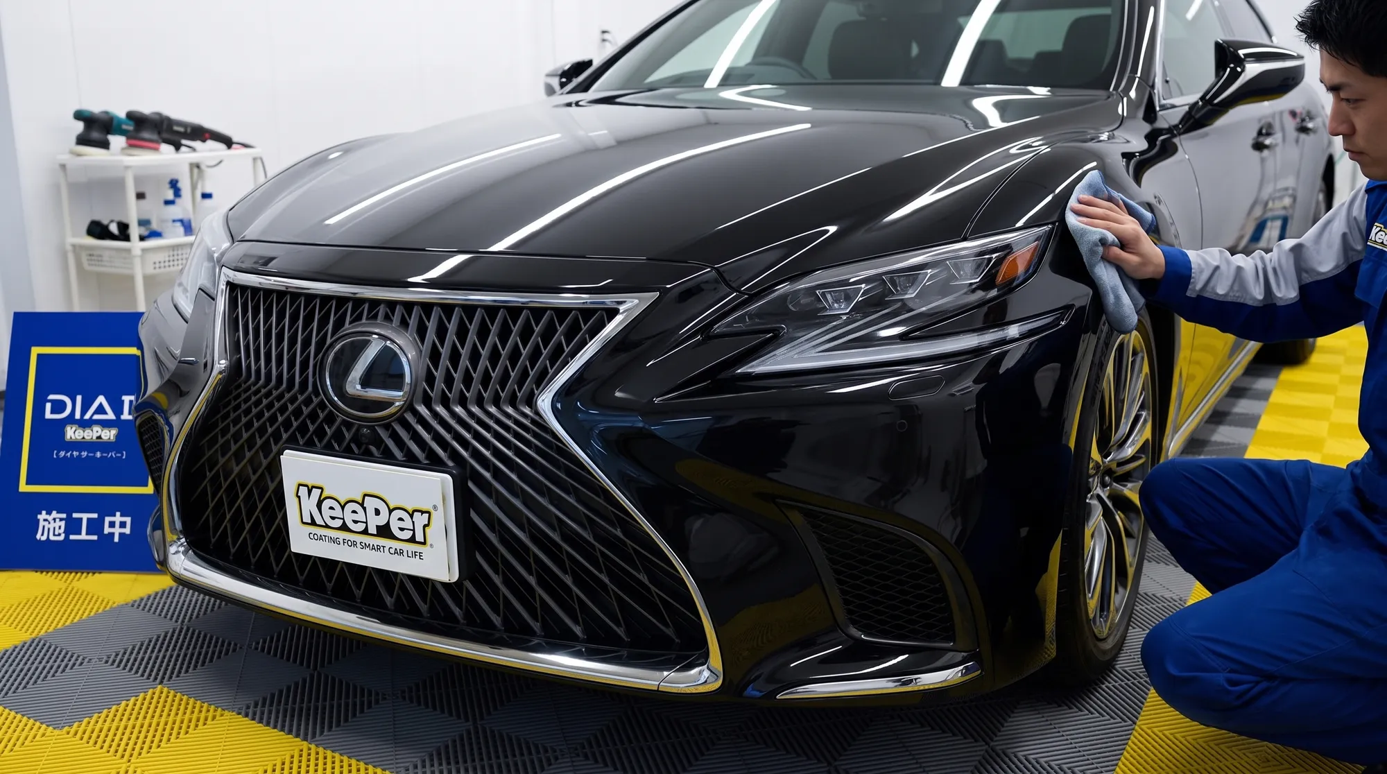 車のコーティングやメンテナンスをローアングルから捉えた画像。艶のある黒系ボディに光が反射するディテールが美しく、重厚で締まった色味が高級感を演出するシーン。