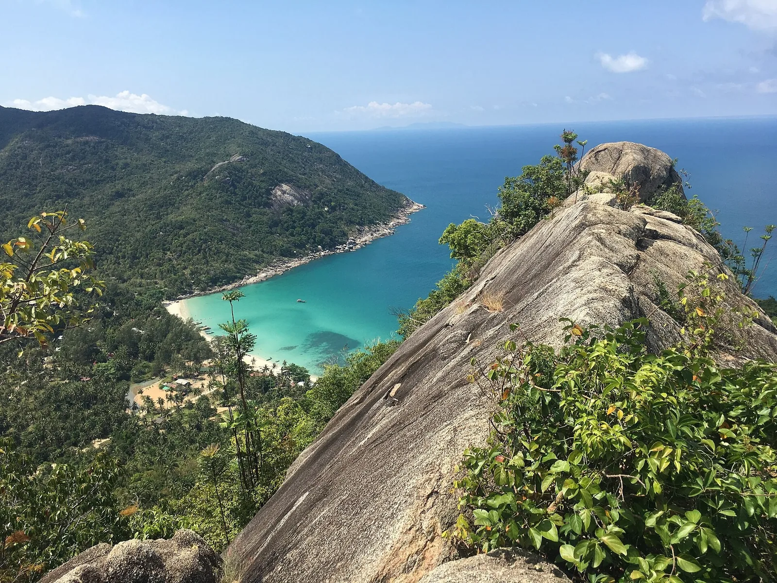A sweeping view over a tropical bay with turquoise water and forested headlands