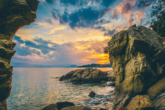 A rocky coastline beneath a wide sunset sky