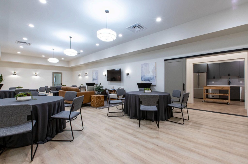 Spacious reception area with round tables, lounge seating, and adjacent catering kitchen at Bunker Family Funerals.