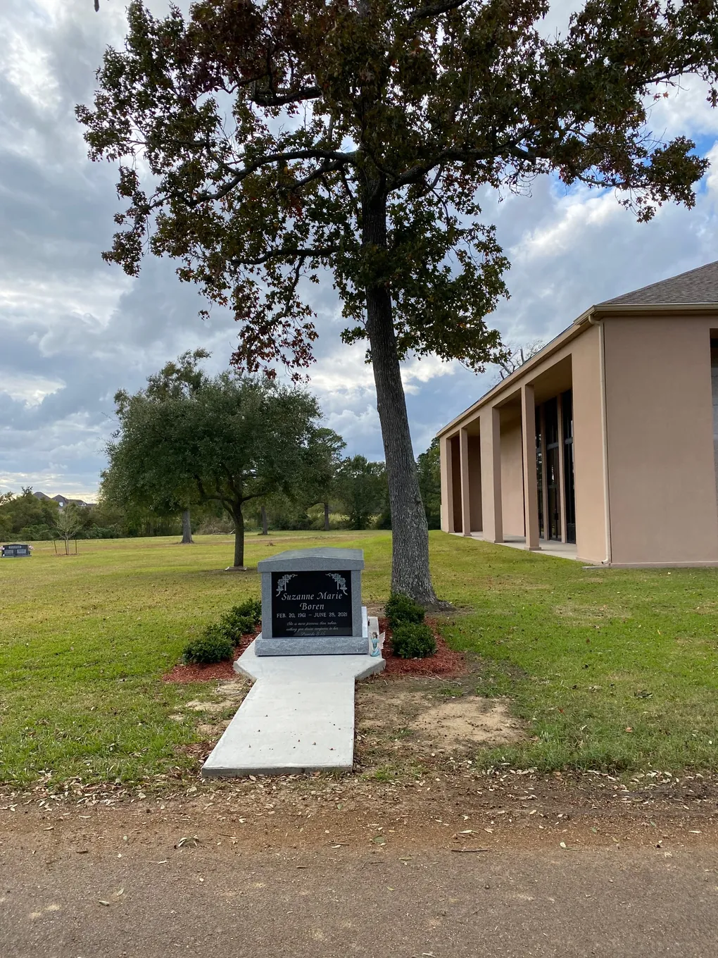 Upright granite monument beneath an oak tree at Oak Bluff Memorial Park