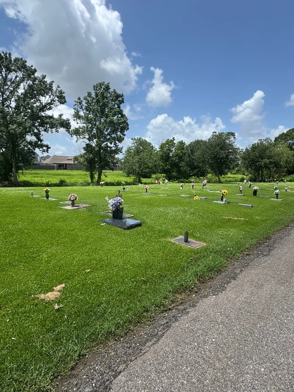 Flush lawn markers under a blue sky at Oak Bluff Memorial Park
