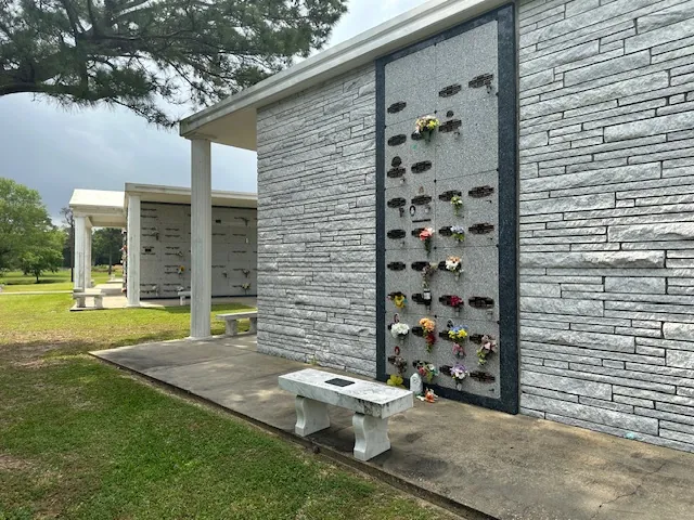 Grey stone cremation niche wall with a memorial bench at Oak Bluff Memorial Park