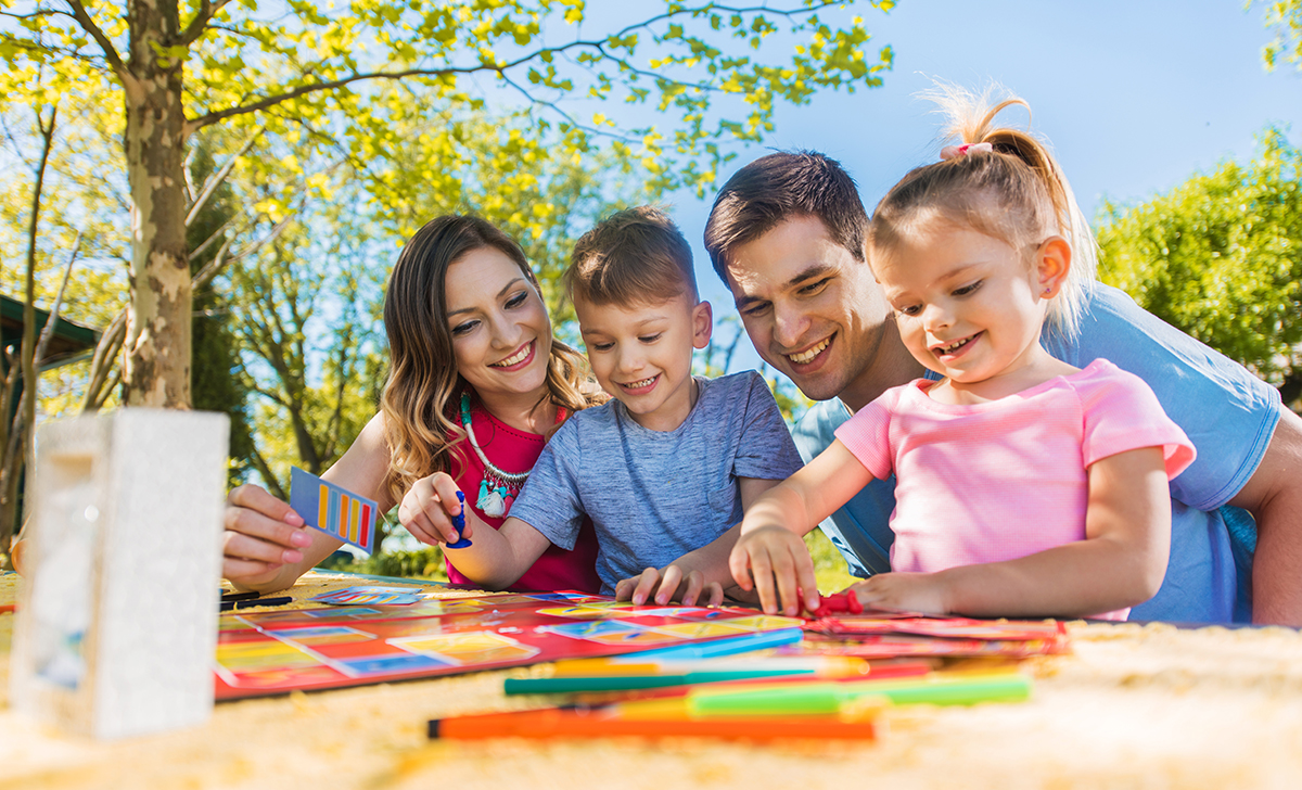 Happy family spending a day outdoors and playing board game.