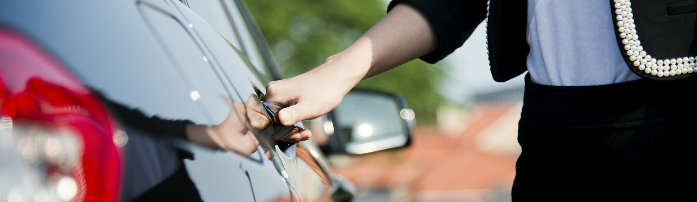 Closeup of a businesswoman opening a car door.