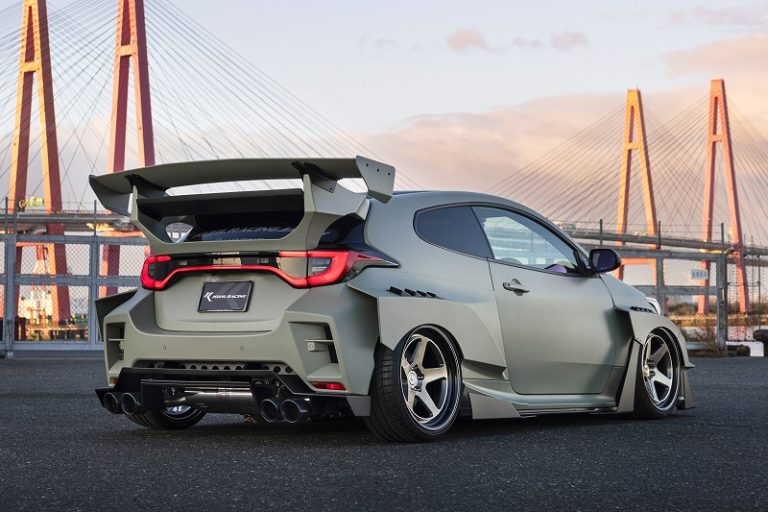 マットグリーンのワイドボディ・ローダウン車のリアビュー。大型ウィングと4本出しマフラー。