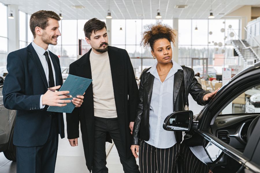 three people looking at a vehicle in a car dealership