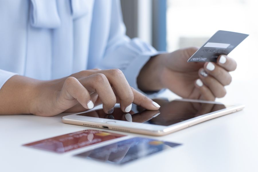 Woman holding credit card and using a tablet