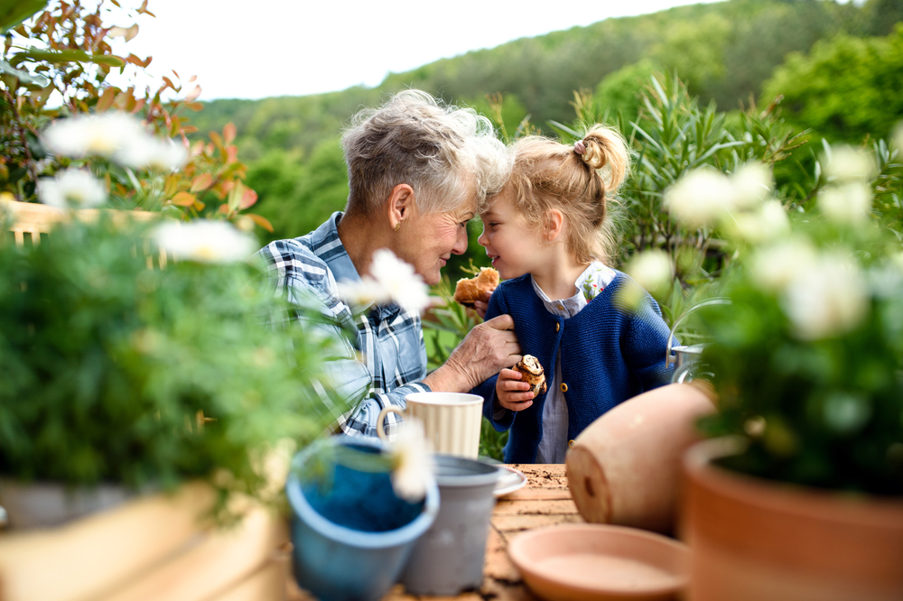 Grandma and granddaughter tend to potted plants outside
