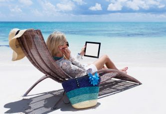 Woman relaxing on the beach and listening to music on her digital tablet computer