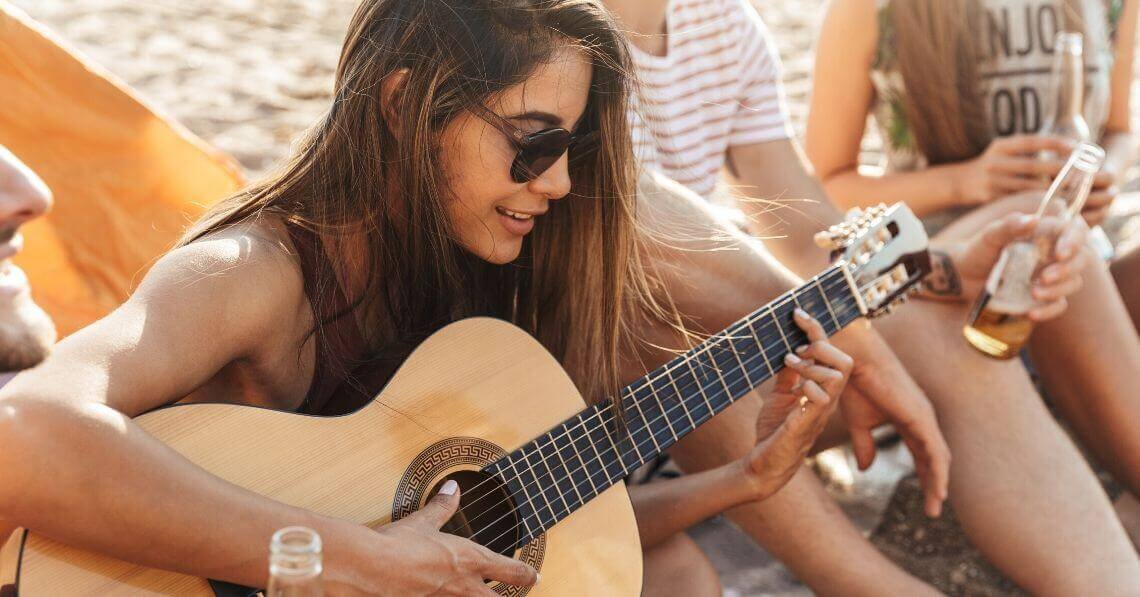 Young woman playing guitar at the beach party