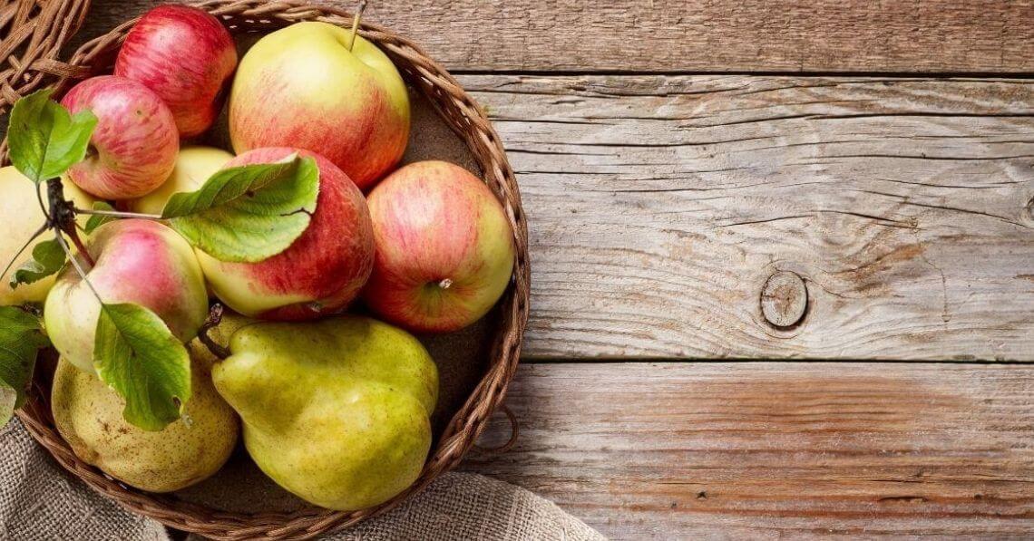 Apples and pears in a basket on a wooden table