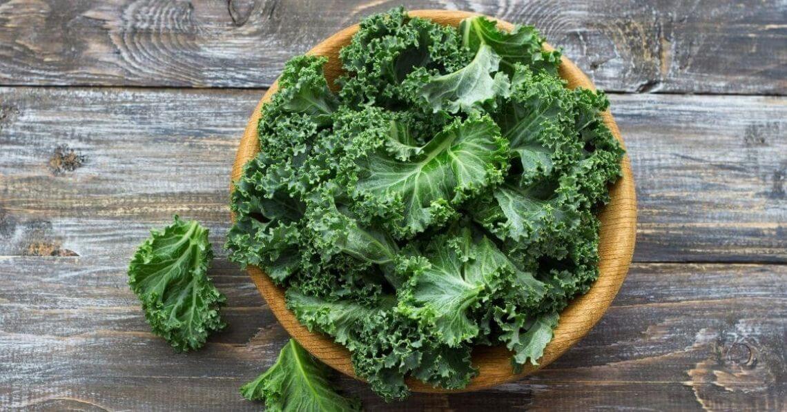 Kale in a wooden bowl on a wooden table