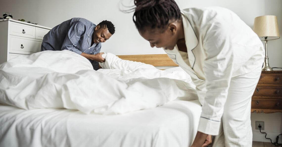 A young couple making the bed in the morning