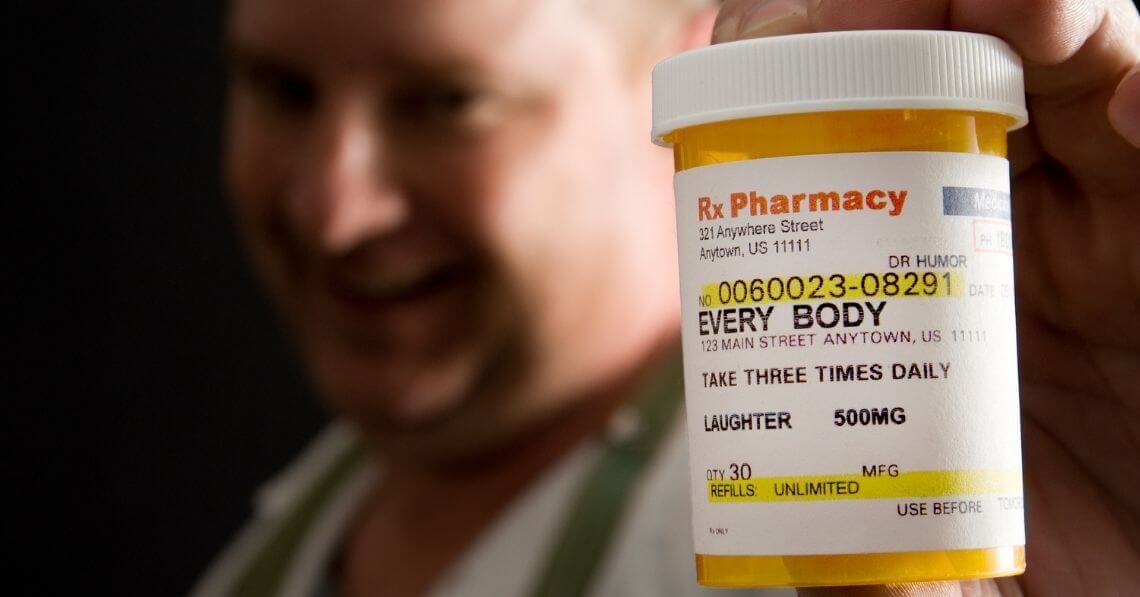 Man holding prescription bottle of "laughter"