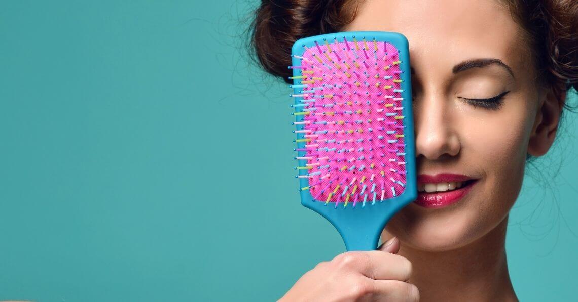 Playful young woman with a colorful hair brush