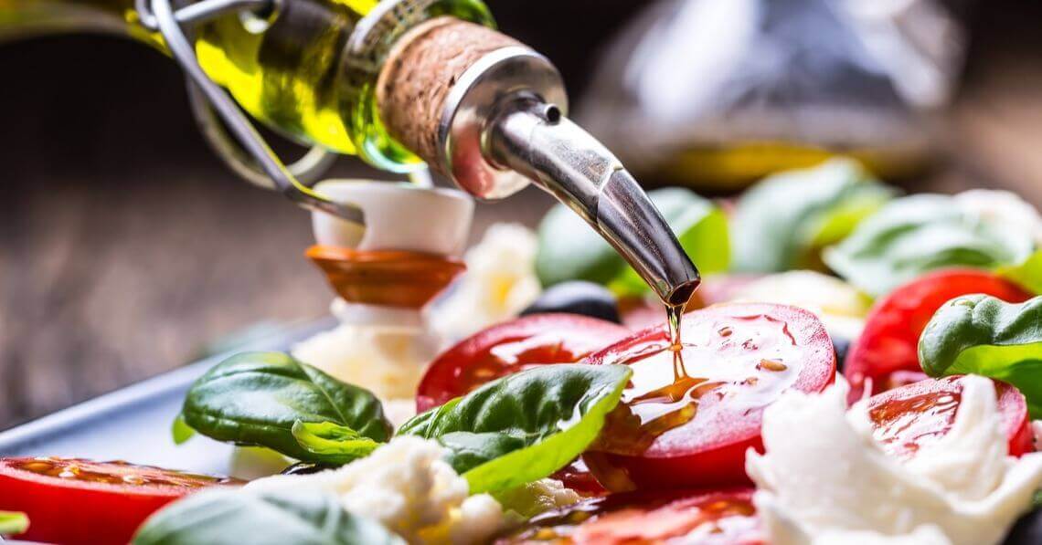 Adding olive oil on a caprese salad