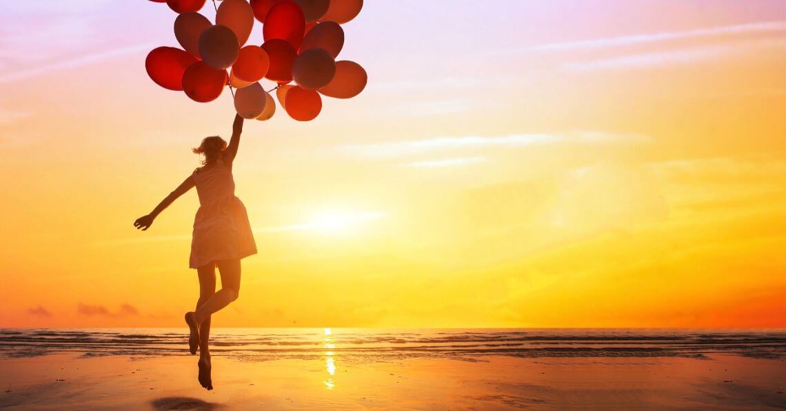 A woman holding onto several red balloons