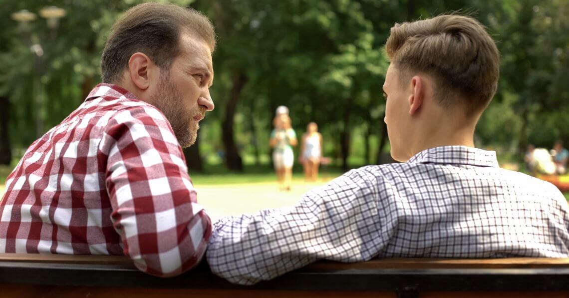 a couple of men sitting at a table looking at each other