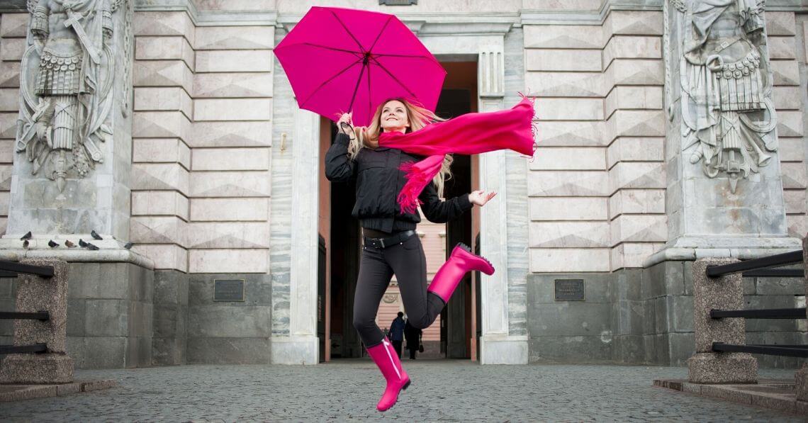 Playful woman jumping in the street with an umbrella