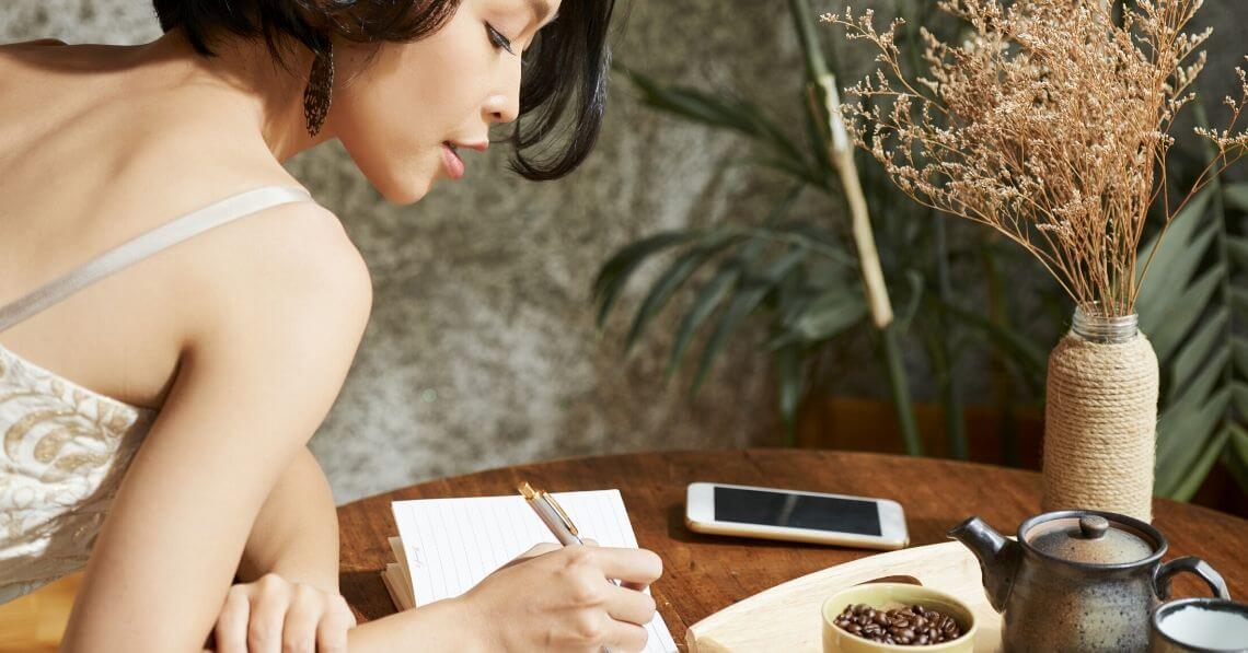 Young woman writing on her gratitude journal