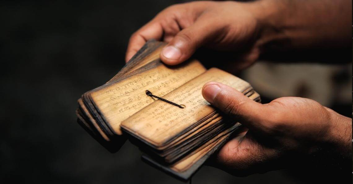 man holding an old mantras book