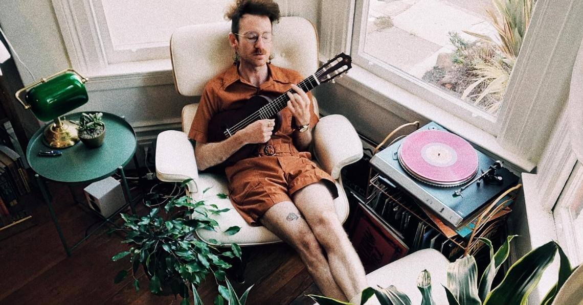 man listening to a record while playing his guitar