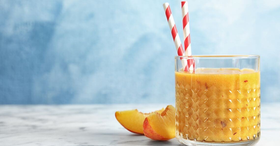 a glass of orange juice with a straw and a slice of orange