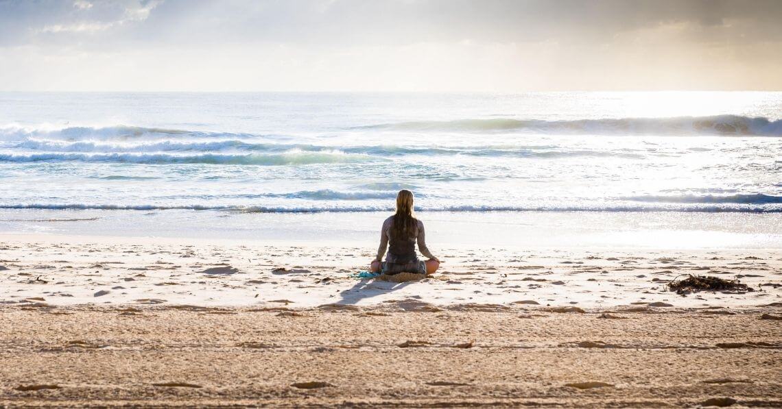 A woman meditating on the beach