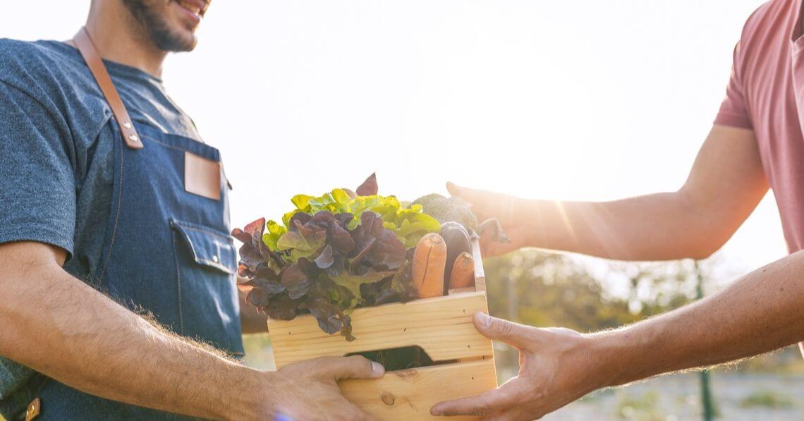 A man handing a woman a box of produce