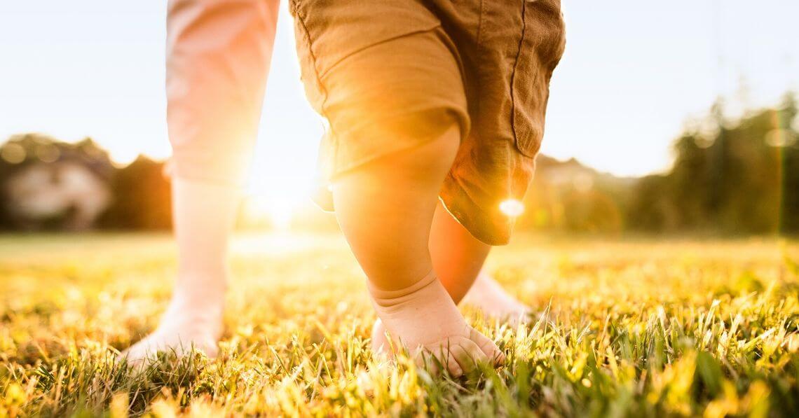 A toddler walking on the grass