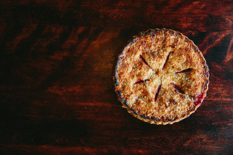 Wildfire Cherry Pie, with a crisp and golden top resting on a dark wooden background