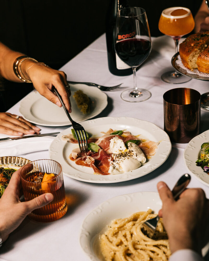 A table spread of dishes and cocktails at Bar Tre Dita
