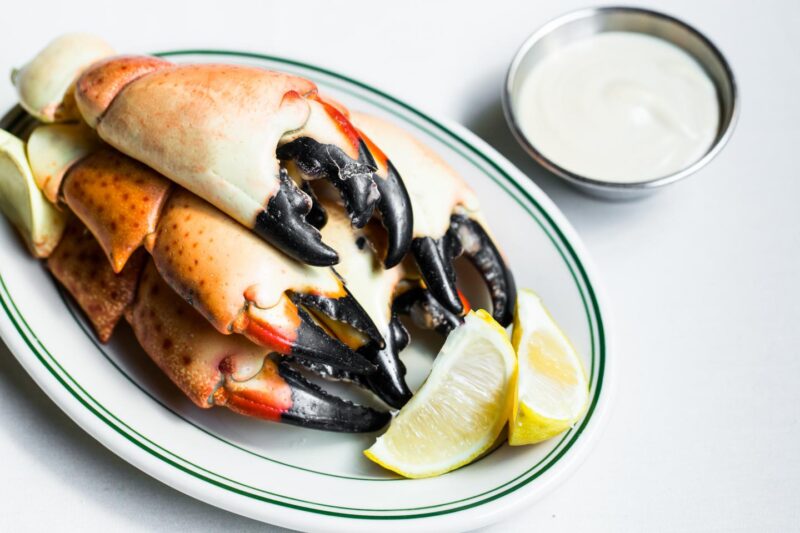 Plate of Joe's Stone Crab Claws with lemon quarters and white sauce on the side