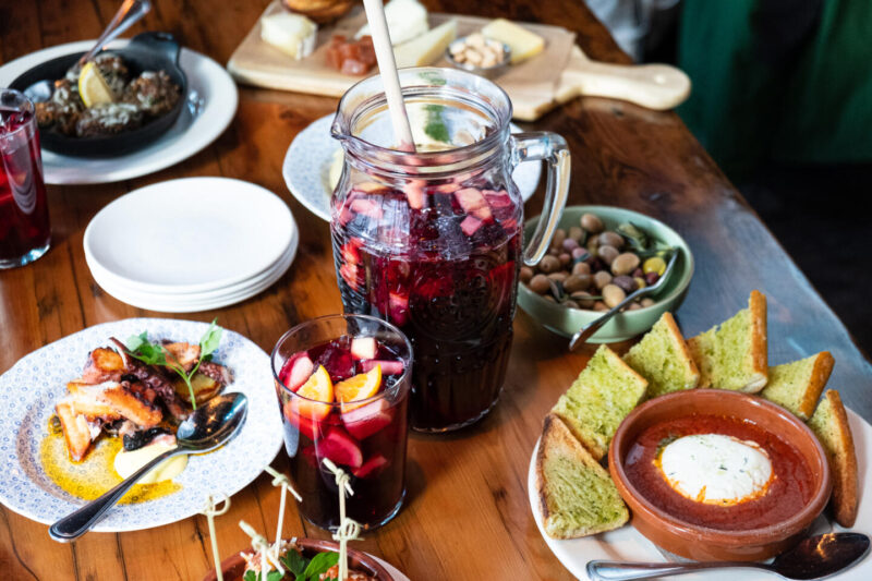 Colorful cheese, tapas plates, and sangria pitcher from Lil' Ba-Ba-Ree-Ba over a wooden table