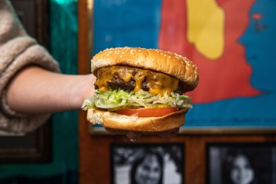 person holding a large cheeseburger in the air