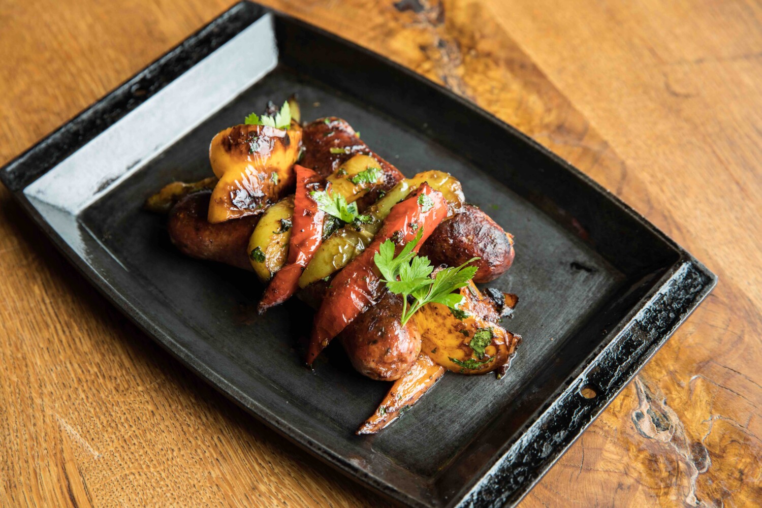 Saranello's Sausage and Peppers dish served on a black plate