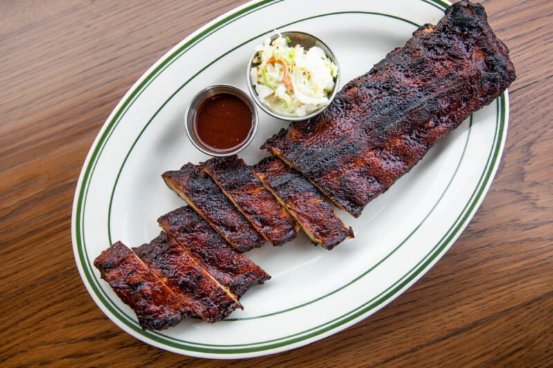 Plate of BBQ Baby Back Ribs from L. Woods grilled to perfection, with slaw and sauce on the side