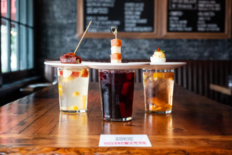 three glasses of beverages from Lil Ba Ba Ree Ba with bite-sized pintxo plates on top