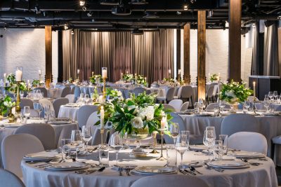 Dalcy event hall. Multiple tables set with plates, glasses, and a bouquet of flowers in the middle.