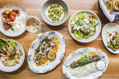 overhead photo of a variety of dishes including hummus, kebabs and stracciatella