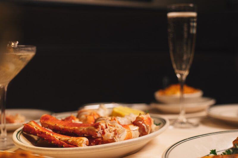 A plate of crab legs with a glass of bubbly and a martini on a table