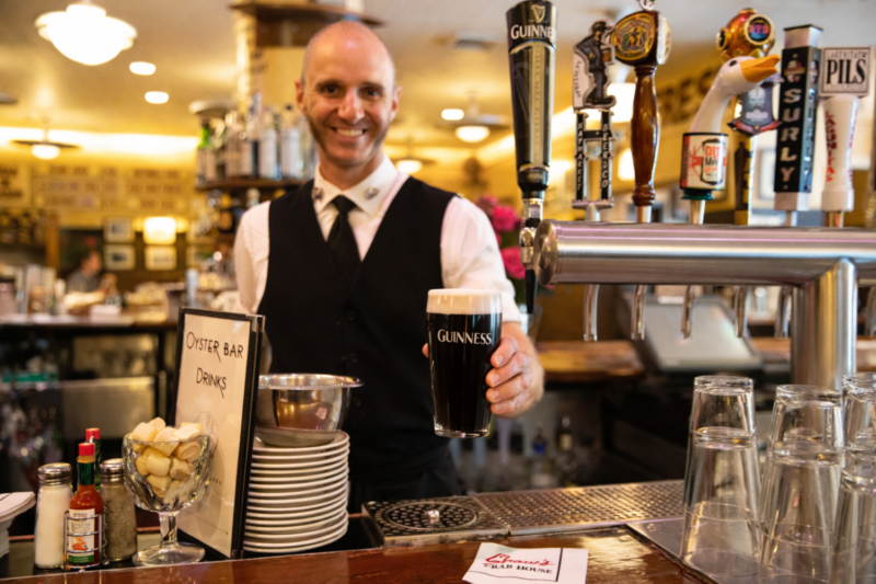 A bartender at Shaw's serves a glass of Guinness beer over the bar